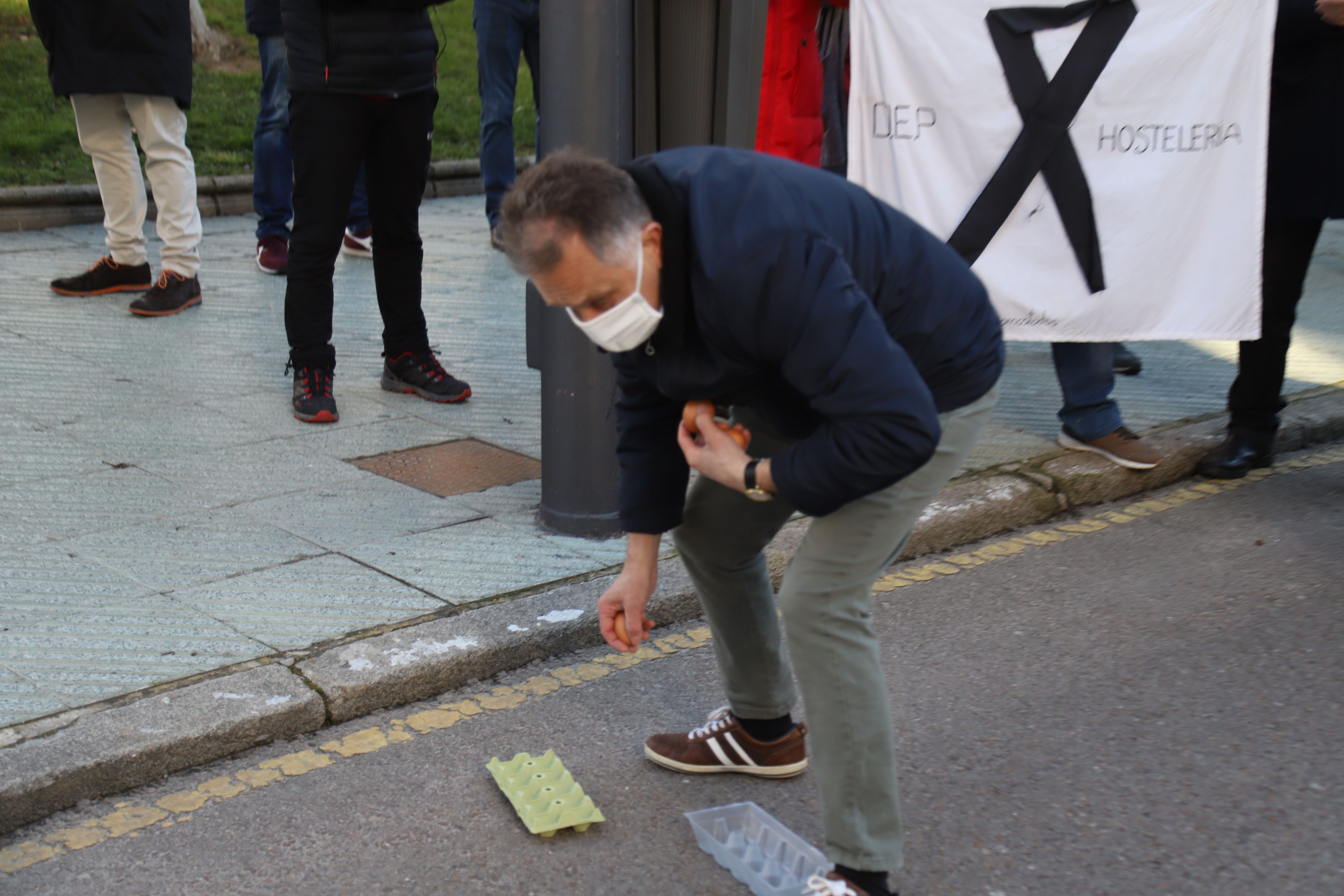 Un manifestante por el sector de la hostelería arroja huevos contra la delegación de la Junta 